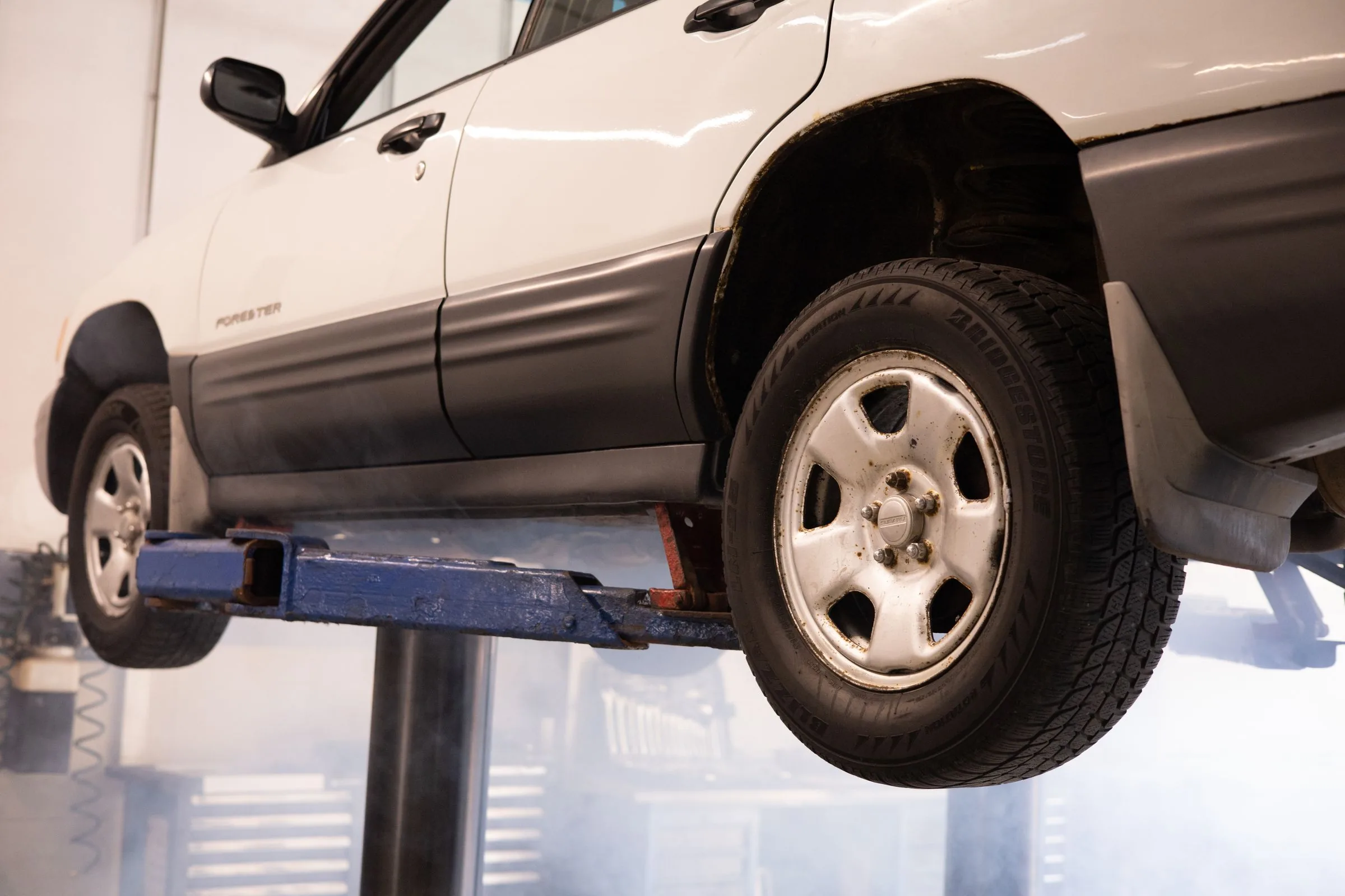 Clean professional automotive workshop with a vehicle raised on a service lift